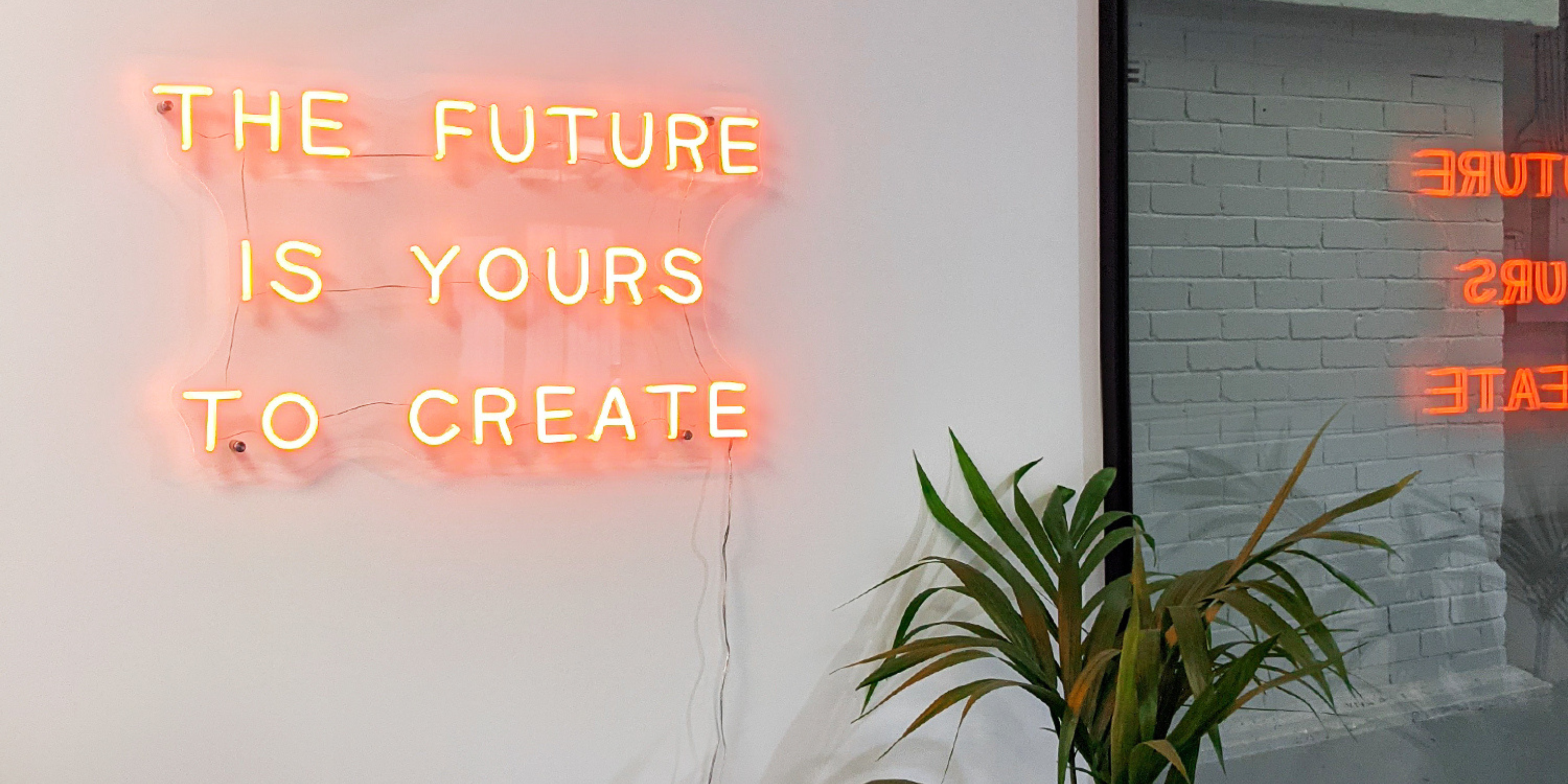 an orange neon light which reads The future is yours to create